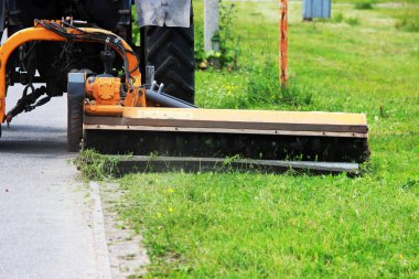 Meme kentsel çimenler üzerinde çim mows bir traktör. kaldırım ve kaldırım yakın çim kesme