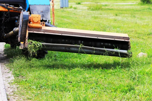 Meme kentsel çimenler üzerinde çim mows bir traktör. kaldırım ve kaldırım yakın çim kesme