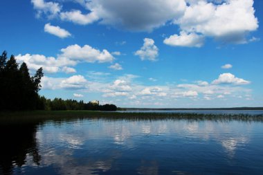 Beyaz bulutlar sudaki yansıması ile yaz aylarında göl Vysokinskoye. Leningrad Region, Rusya Federasyonu