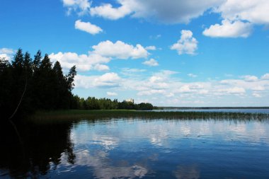Beyaz bulutlar sudaki yansıması ile yaz aylarında göl Vysokinskoye. Leningrad Region, Rusya Federasyonu