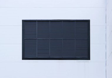 Bir pencerede bir büyük sanayi Alışveriş Merkezi havalandırma ızgaraları şeklinde dış jaluzi ile kapalı. Açık mavi renkli.