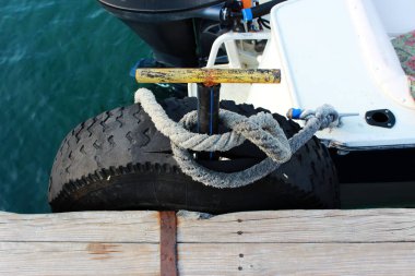 denizin kenarında ahşap bir iskele için küçük bir tekne palamarla. Lastikler Kiralık tekerlekler gelen gemi zararlardan korumak.