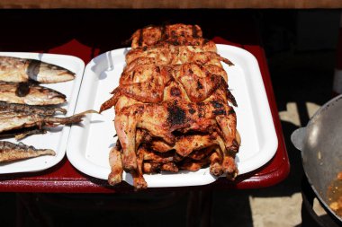 düzleştirilmiş ve ızgara tavuk ızgara siyah deniz kenarında dolgu bir açık ateşe tamamen pişmiş. Çekim röportaj. Kırım Cumhuriyeti.