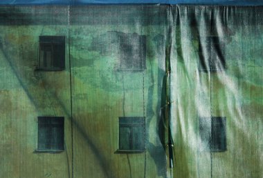 Yeşil Mesh penceresi olan eski ev bina yıkım ve yayalar alçı dökülme üzerinden eski tarihi bina korur.