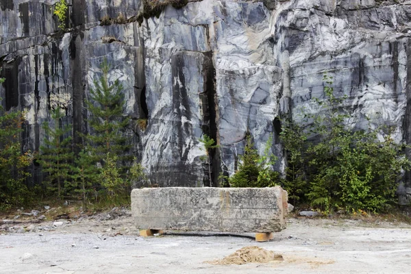 gray natural marble with white streaks in the canyon, deposit, Karelia. A stone bar in the form of a antivandal bench rests on wooden planks