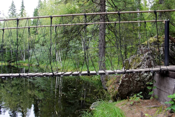 En hängande bro över floden Tohmajoki, där vattenfallen är. Ruskeala, Karelen — Stockfoto