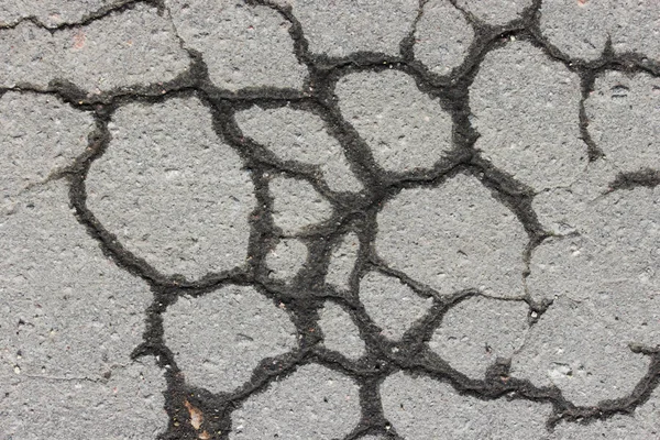 Szary asfalt z pęknięcia, mokre od deszczu jesienią. — Zdjęcie stockowe