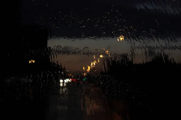 Homecoming. Bokeh lights, wet blurred view of road traffic in Gatchina on a rainy tonight through the bus front window. Raindrops and traces from the janitors on the glass window of the bus — Stock Photo, Image