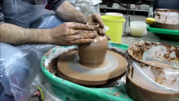 陶芸家の車輪の上に14年の経験を持つブルガリア人のマスターは 内側と外側から未来の鍋の壁に両手で形を与え 彼をポットベリーにします — ストック動画