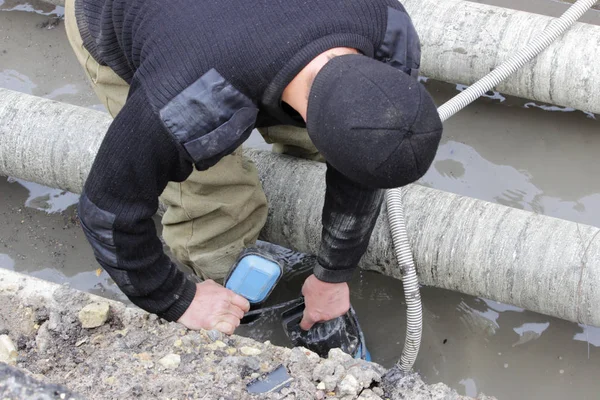 A worker from the emergency water utility brigade holds a pump and pumps out water from the emergency ditch. reportage photography, Russia