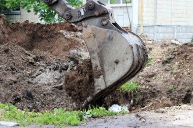 Ekskavatör kazadan sonra ortadan kaldırılması ile bir kova su boruları ile hendek gömüyor. Çekim röportaj.