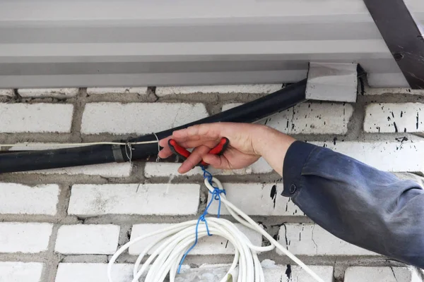 Un electricista de la brigada desconecta el cable desde el que se alimentaron las luces de advertencia rojas en la cerca de reparación durante la eliminación del accidente en la empresa de suministro de agua. fotografía de reportaje — Foto de Stock