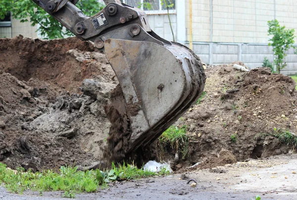 Excavator buries a ditch with a bucket with water pipes after the elimination of the accident. Reportage shooting. — Stock Photo, Image