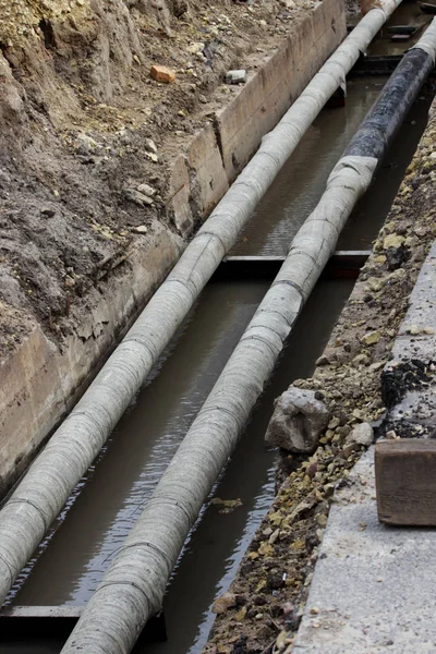 water pipes, insulated roofing sheets during repair in a ditch filled with muddy liquid