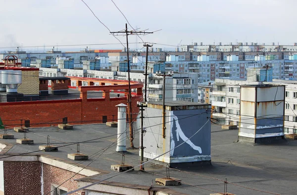 view from the flat roof of a multistory building covered with ruberoid, railing. column with electrical wires, television antenna and ventilation pipe. view of the city of Arkhangelsk