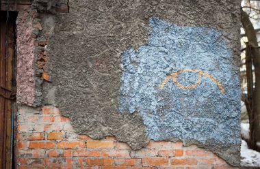 Terk edilmiş eski tuğla ev, çimentoyla kaplanmış, mavi arka planda bir göz şeklinde grafiti yapılmış. Evsizlerin ve uyuşturucu bağımlılarının takıldığı bir yer. Petersburg, Rusya.