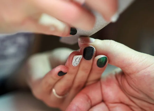 Servicio de manicura de uñas sierra y suaviza las uñas del cliente utilizando una lima. rodaje de reportajes —  Fotos de Stock