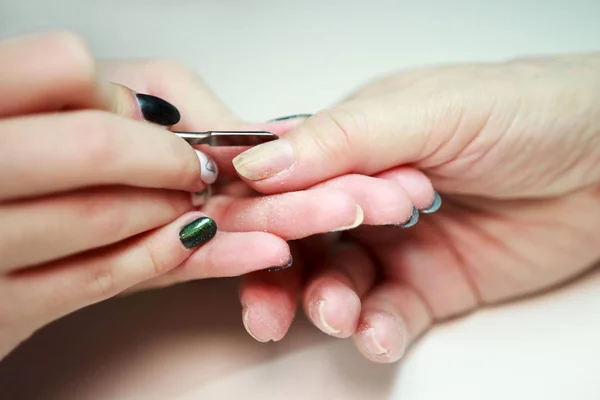 Manicura de servicio de uñas hace una manicura mujer anciana con una herramienta de metal - una lanceta con una espátula en el extremo. Saliendo de la cutícula de las uñas. reportar disparos . — Foto de Stock