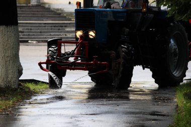 Bir karavanda fıçısı olan traktör şehrin kaldırımlarına su döker, su akıntıları zemine akar..