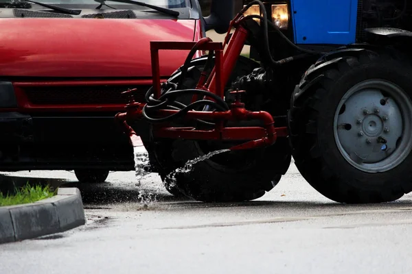 Tractor con un barril en un remolque vierte agua sobre las aceras de la ciudad, arroyos de agua fluyen hacia el suelo . — Foto de Stock