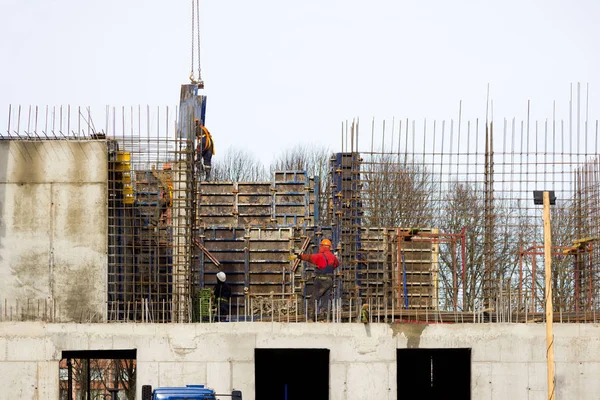 De arbeider en de kraanmachinist laden de auto uit met gewapend betonnen wanden voor de bouw van een groot wellnesscentrum met een zwembad van moderne technologie met beton gegoten versterkt en vormgegeven — Stockfoto