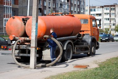 İşçi gece adamı kanalizasyon sisteminden sokaktaki kapaktan atık su pompaladı. Sokak temizleme borusunda kanalizasyon işçisi.