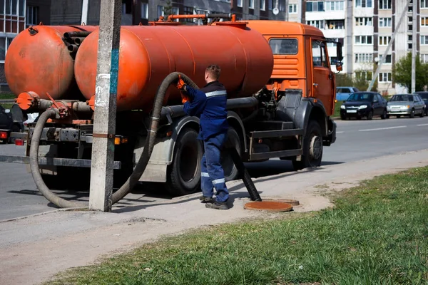 İşçi gece adamı kanalizasyon sisteminden sokaktaki kapaktan atık su pompaladı. Sokak temizleme borusunda kanalizasyon işçisi.