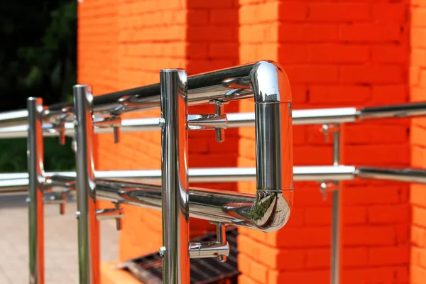 Corrimão de aço metálico com uma saída para inválido perto das instalações. Parede de tijolo pintada com tinta laranja — Fotografia de Stock