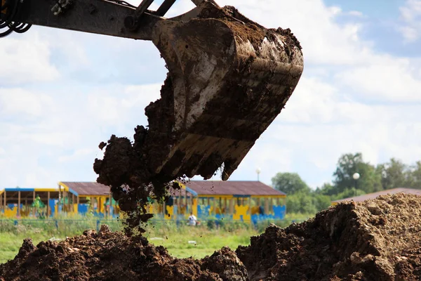 El trabajo sucio del cubo de la excavadora, que cava tierra en el terreno baldío cerca de la casa para detectar tuberías de agua de choque. reportaje . — Foto de Stock