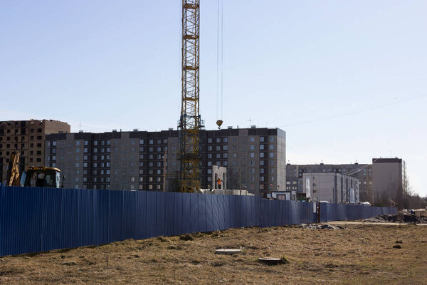 a worker in an orange helmet directs the unloading of concrete slabs with a crane on the construction site of a multi-storey multi-dwelling prefab house. Gatchina. reportage
