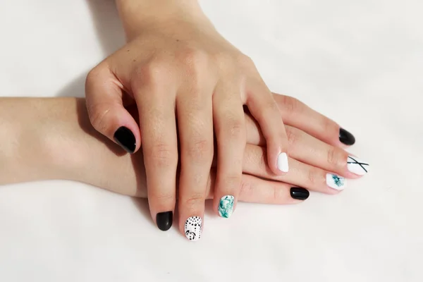 Mãos de uma jovem com manicure verde, preto e branco, com adesivos . — Fotografia de Stock