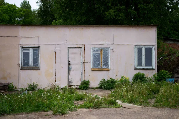 Pink barn with plaster on wall stands in the yard. the door is locked. three windows — 스톡 사진