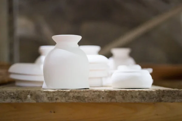 Articles of clay made by slip forming using plaster molds a master with 13 years of experience. drying on a rack with shelves from chipboard. sockets, glasses, plates. — 图库照片