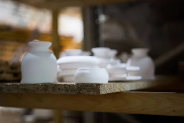 Articles of clay made by slip forming using plaster molds a master with 13 years of experience. drying on a rack with shelves from chipboard. sockets, glasses, plates. — 图库照片