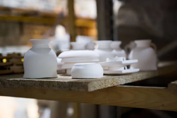 Articles of clay made by slip forming using plaster molds a master with 13 years of experience. drying on a rack with shelves from chipboard. sockets, glasses, plates. — 图库照片