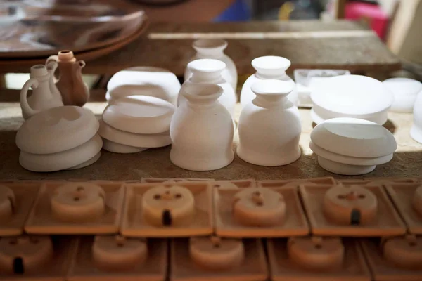 Articles of clay made by slip forming using plaster molds a master with 13 years of experience. drying on a rack with shelves from chipboard. sockets, glasses, plates. — 图库照片