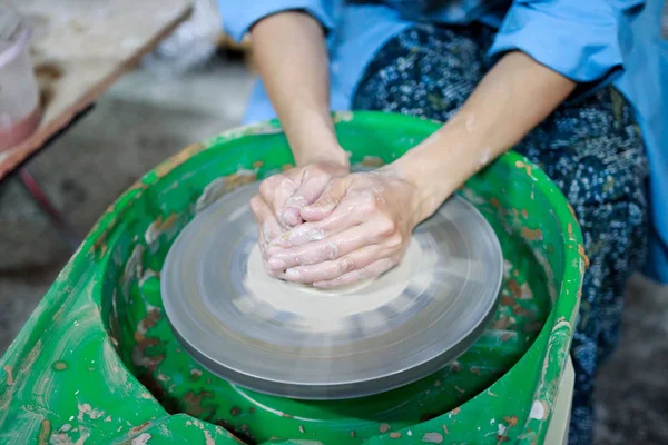 A novice student in the first lesson in pottery tries to make a product from clay on a potter's wheel. reportage. clay centering. Incorrect hand setting — Stock Photo, Image