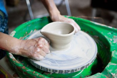 Çömlekçilikle ilgili ilk derste çömlekçi çarkındaki beyaz çamurdan bir ürün yapmaya çalışan genç bayan çömlekçi. Rapor veriyorum. Küçük sos tepsisi. Çemberden bir ürünü tel telle kesmek.