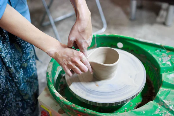 Young woman novice student in the first lesson in pottery tries to make a product from white clay on a potter's wheel. reportage. small sauce pan. making a spout — Stock Photo, Image