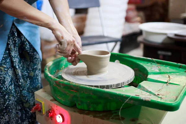 Young woman novice student in the first lesson in pottery tries to make a product from white clay on a potter's wheel. reportage. small sauce pan. making a spout — Stock Photo, Image