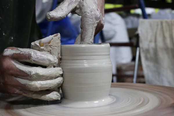 一位拥有13年工作经验的工匠在陶工的轮上拧松了一个圆筒的螺丝- -任何陶瓷产品的基本形式，以及将其塑造成壶的手指。 正确的手部设置. — 图库照片
