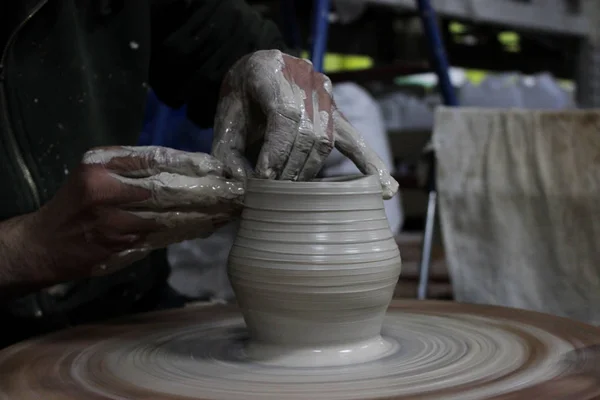 Un artisan avec 13 ans d'expérience dévisse un cylindre sur une roue de potier - la forme fondamentale de tout produit en céramique et les doigts lui ont façonné un pot. réglage manuel correct . — Photo