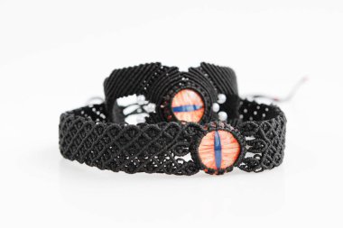 Beyaz bir arka planda, makrome tekniğinde balmumu iplikten kırmızı ejderha gözü boyun ve kol bileziği takan siyah boğaz. El yapımı..