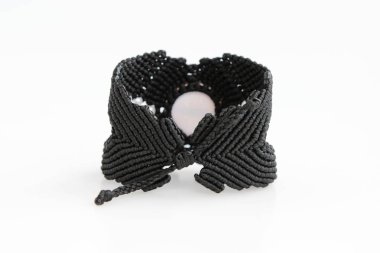 Beyaz arka planda, makrome tekniğinde balmumu iplikten kırmızı ejderha gözü koluna sahip siyah bilezik. El yapımı.