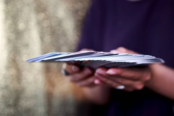 Manos adivinos sostienen una baraja de cartas del tarot sobre un fondo de oro. 63 cubierta de oráculo completo . — Foto de Stock