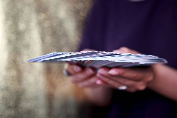 Fortune-tellers handen houden een deck van tarot kaarten op een gouden achtergrond. 63 volledig Oracle deck. — Stockfoto