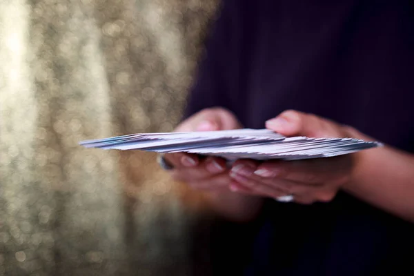 Manos adivinos sostienen una baraja de cartas del tarot sobre un fondo de oro. 63 cubierta de oráculo completo . — Foto de Stock