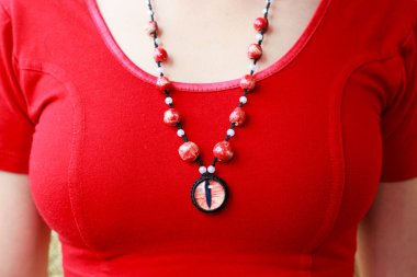 ejderha kırmızı göz kalçası ve seramik boncuklar. Kırmızı arka planda genç bir kızın kolyesi.