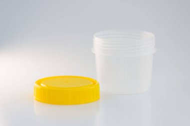 Beyaz arka planda sarı kapaklı şeffaf plastik bir kavanoz. analiz için