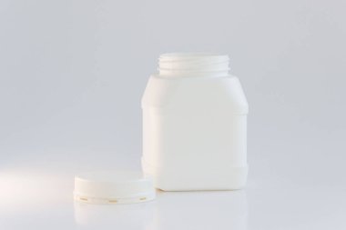 Beyaz arka planda kapağı olan beyaz plastik kavanoz